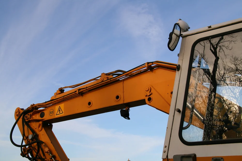 Close-up of an excavator boom and cab against a blue sky